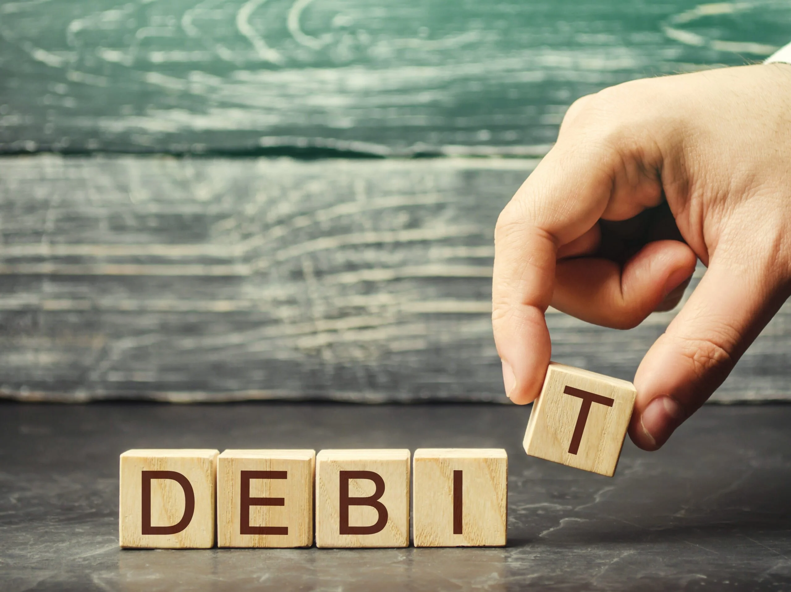 Businessman puts wooden blocks with the word Debit Fundraising company profit Debit account Business and finance concept Accounting company