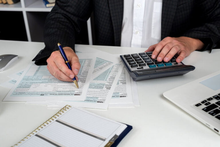 close up of male hand filling US tax form Accountant working with 1040 form