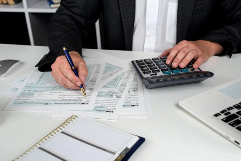 close up of male hand filling US tax form Accountant working with 1040 form