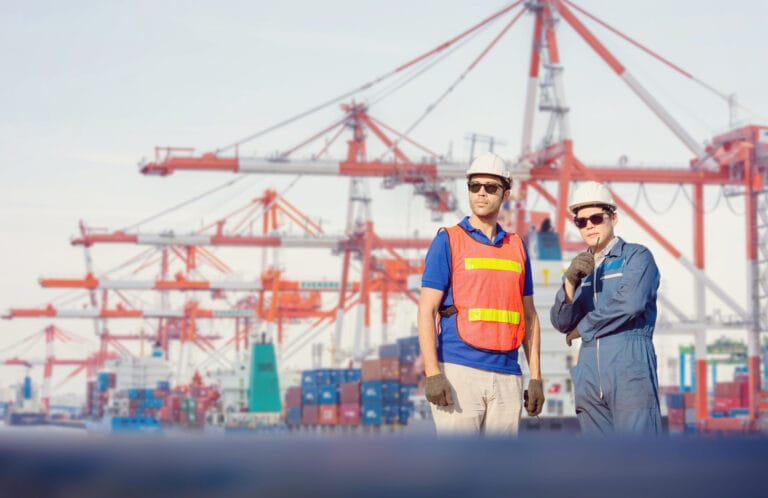 Engineer and Worker man in hardhat and safety vest checking control loading containers box from cargo Teamwork concept