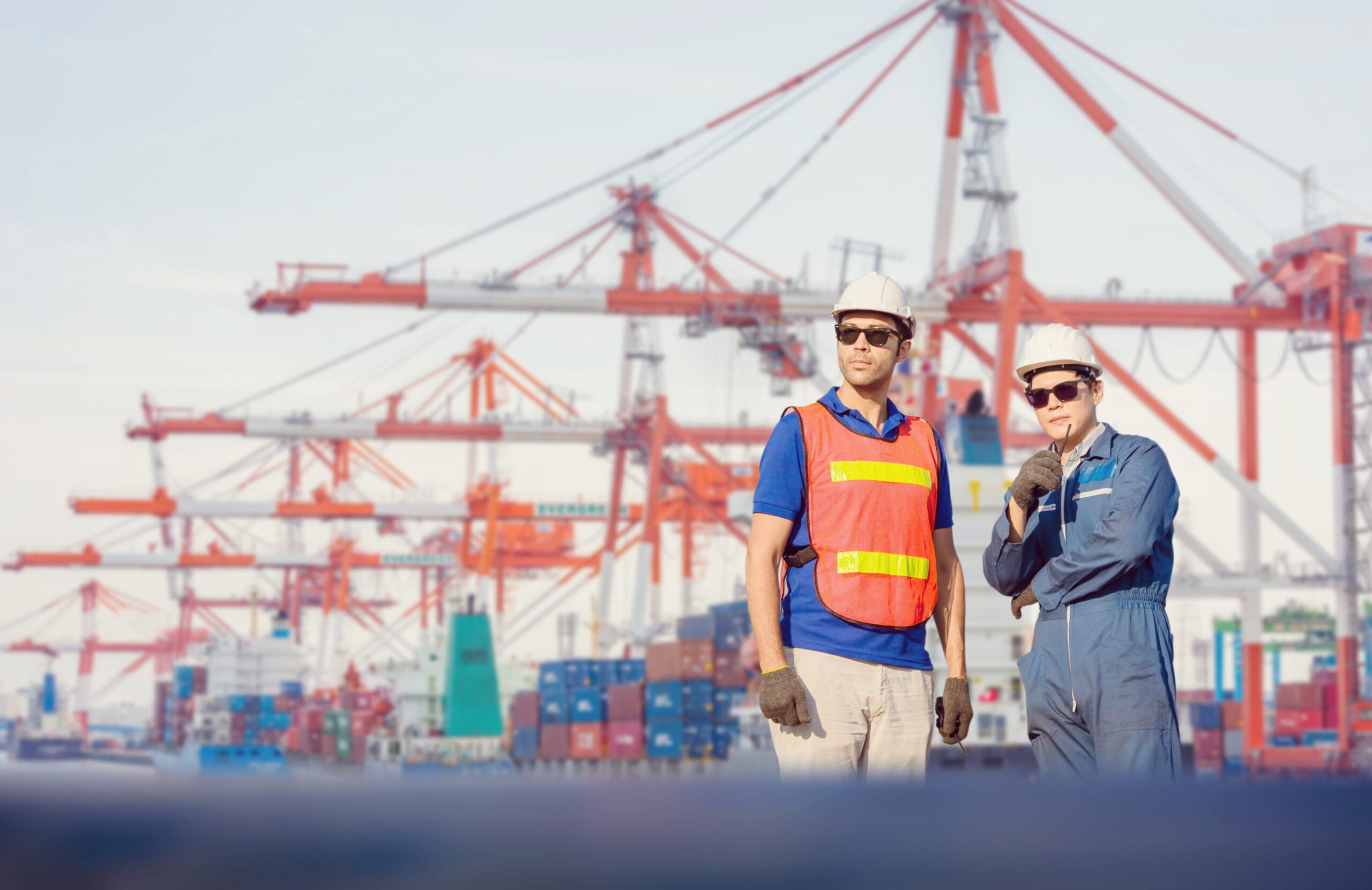 Engineer and Worker man in hardhat and safety vest checking control loading containers box from cargo Teamwork concept